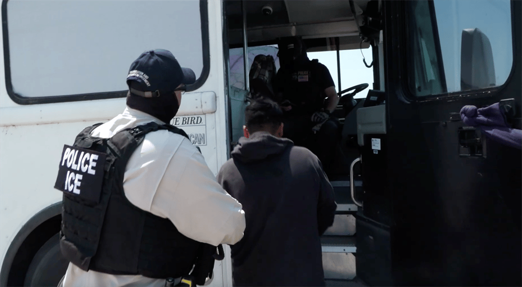 An ICE agent places a detained worker on a bus after an immigration raid at Glenn Valley Foods in Omaha. Courtesy Immigration and Customs Enforcement.